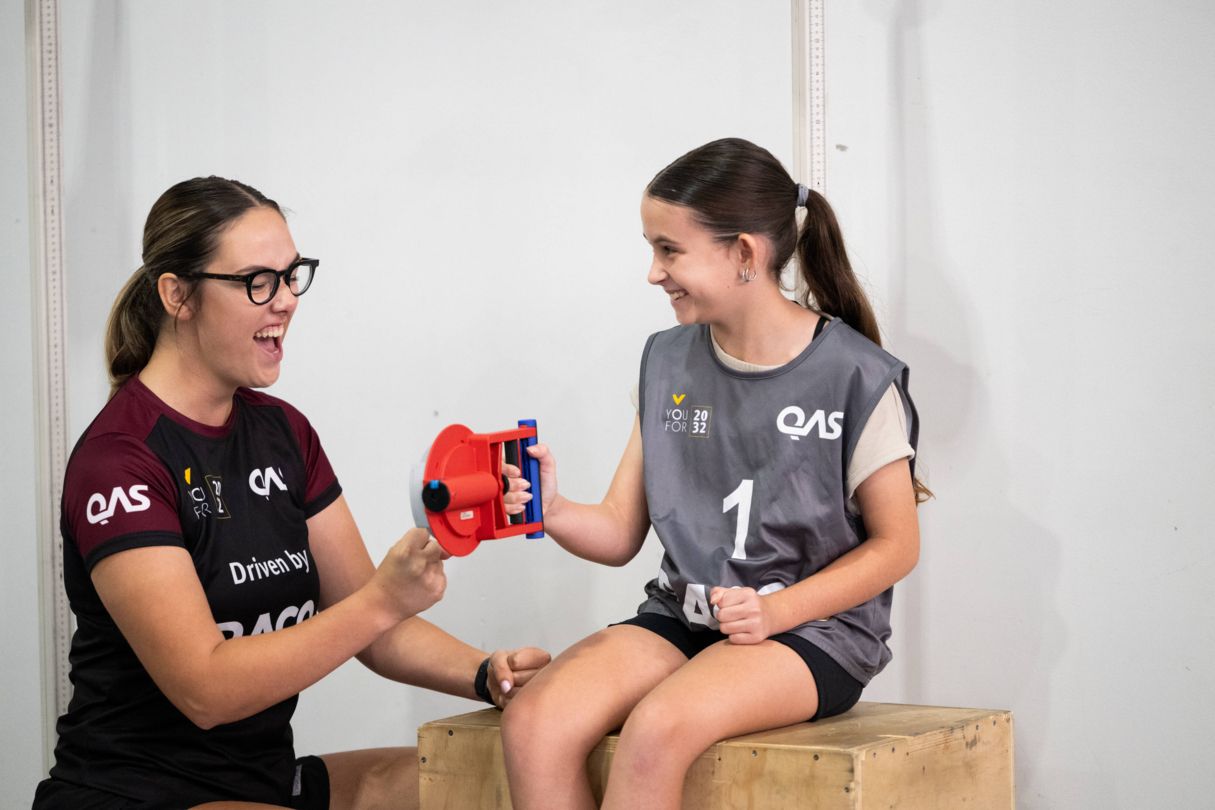 Talent team advisor taking young female athlete through testing exercise using a handgrip exercise.