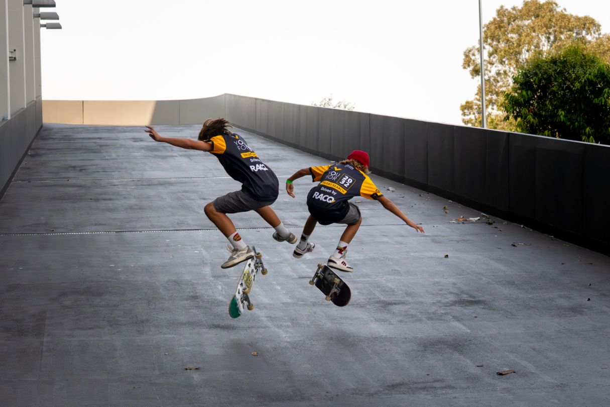 Two young boys on skateboards jumping in air.