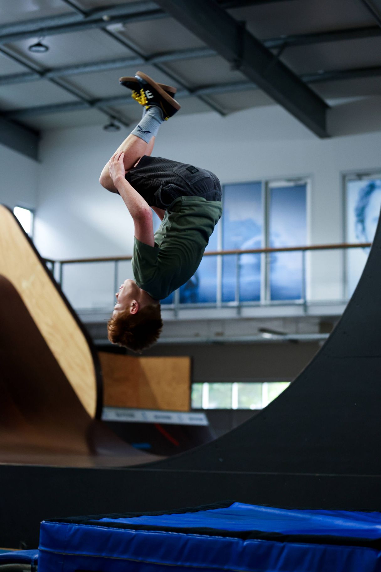 Young male athlete doing a flip in the air over a gymnastic mat.