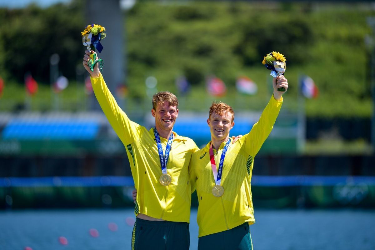 Tom Green and Jean van der Westhuyzen holding up their winning flowers after winning gold at the Tokyo Olympic Games.