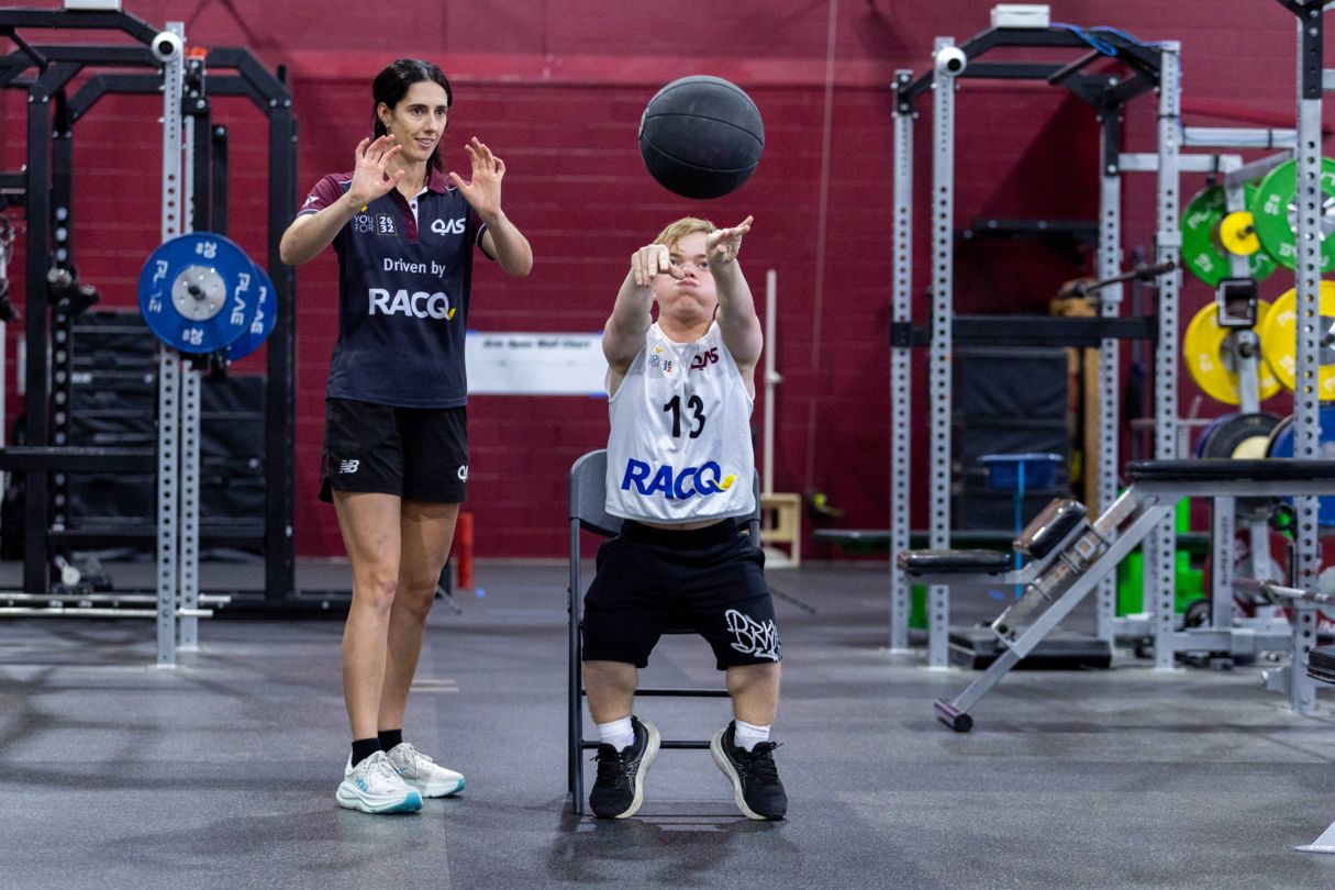 Young athlete throws a medicine ball with a YouFor2032 Talent team advisor watching on
