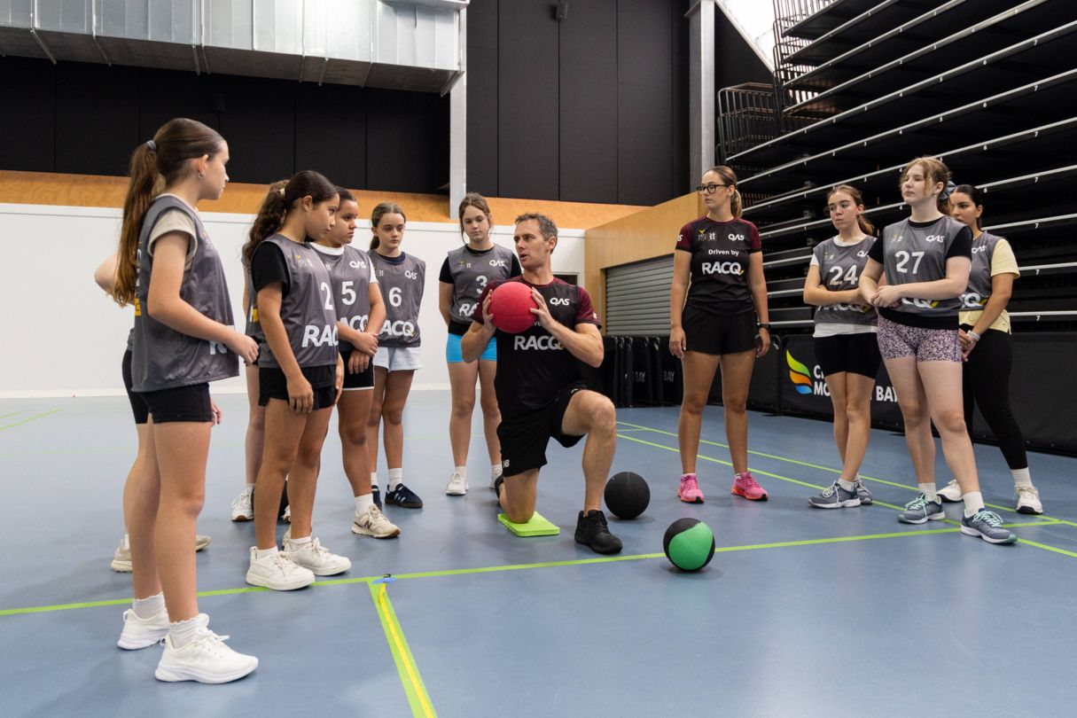 QAS YouFor2032 Talent Team member showing group of young athletes a ball throw testing exercise.