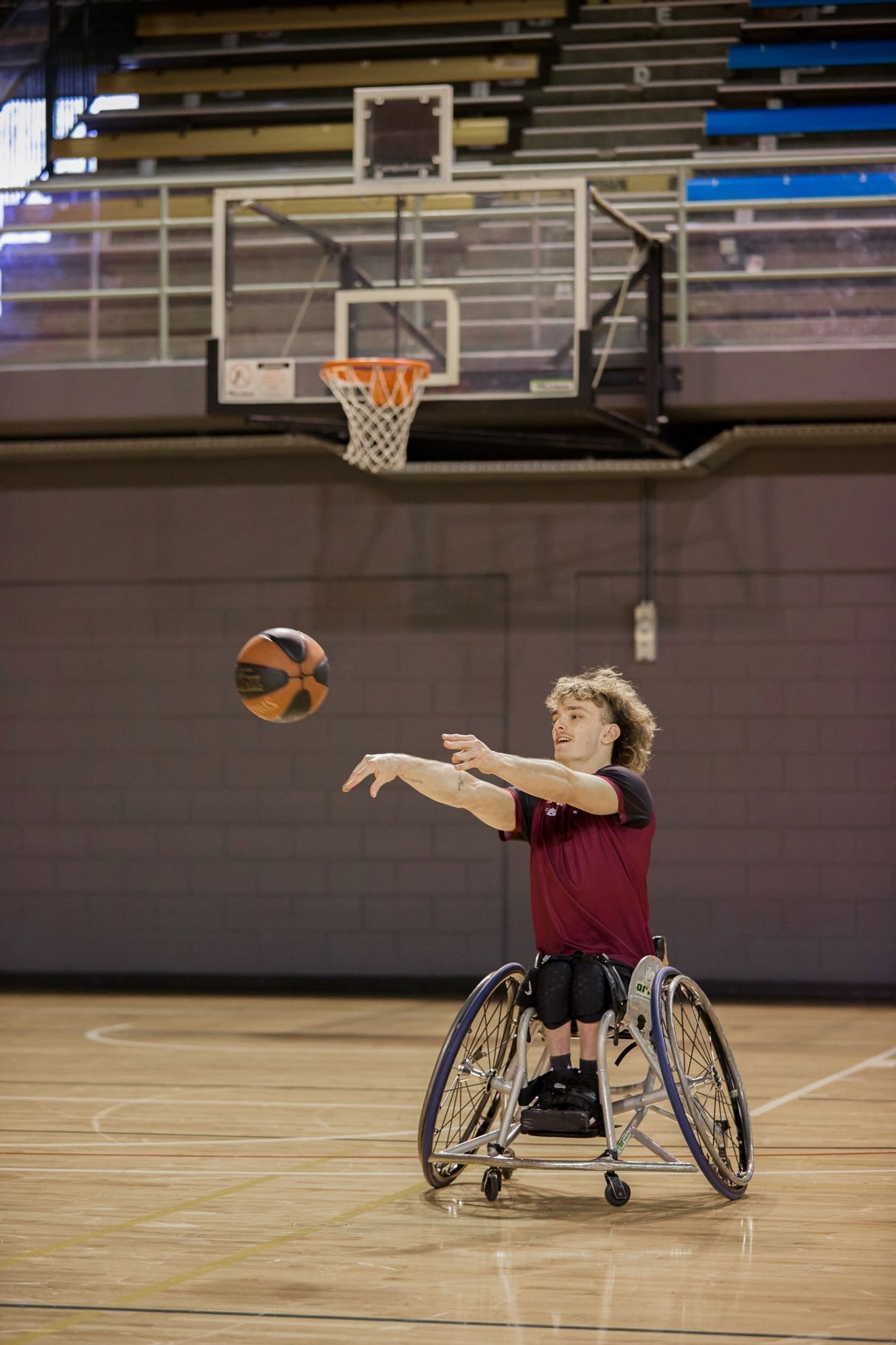 Eithen Leard passes a basketball while wearing a QAS shirt