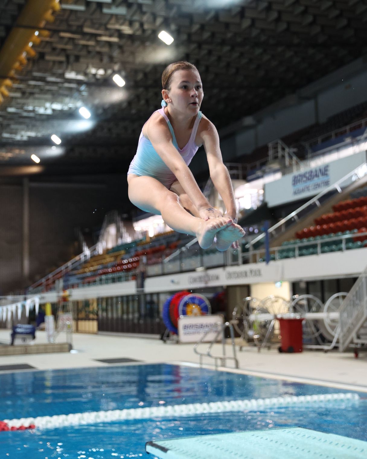 Young female doing a flip into a pool.