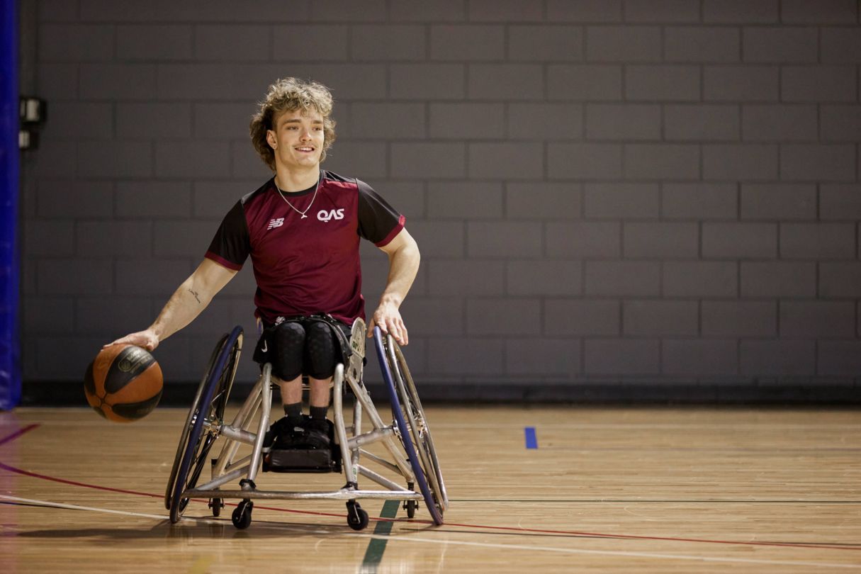 Eithen Leard bounces the basketball while wearing a QAS shirt