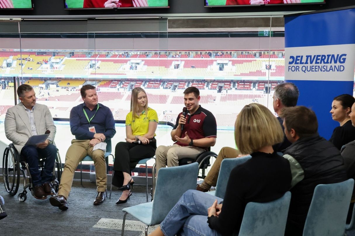 Tristan Orchard is holding a microphone and speaking on a panel discussion.