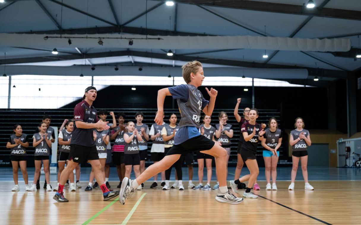 Young athlete tests his speed for the YouFor2032 Talent Search, cheered on by QAS staff and other athletes.